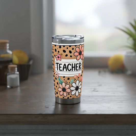 Tumbler with floral design and 'Teacher' text on a wooden surface.