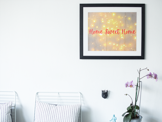 Framed artwork with 'Home Sweet Home' text on a wall above a white chair.
