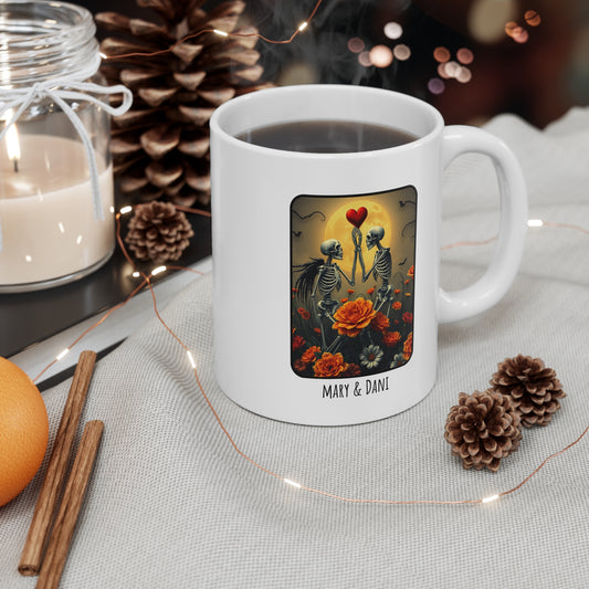 White mug with a decorative design featuring skeletons and flowers, surrounded by festive items like pine cones and candles.
