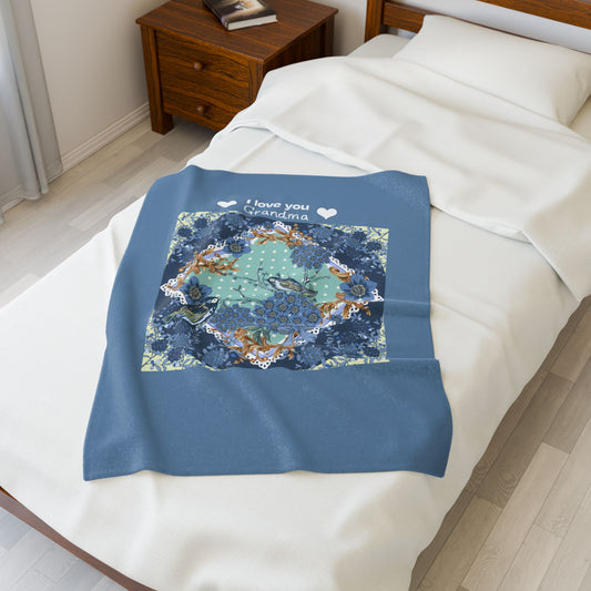 Blue blanket with floral pattern and 'I love you Grandma' text on a bed